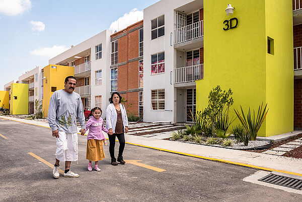 Family of three in front of housing area